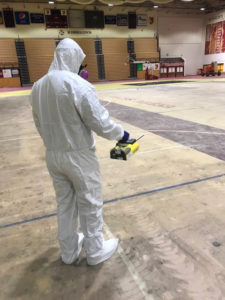 man in a hazmat suit cleaning the gym floor