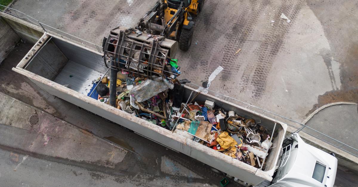 An aerial view of a skid steer loader loading a truck with waste material transferred for further sorting, treatment, and recycling.