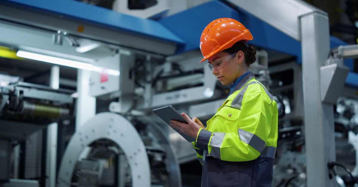 A close-up of an engineer looking at a tablet computer in an energy company. She's also wearing a hard hat.