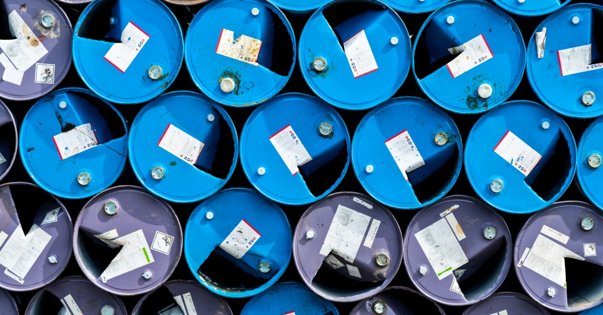 Rows of blue and purple chemical storage drums with identification labels arranged tightly in an overhead view.